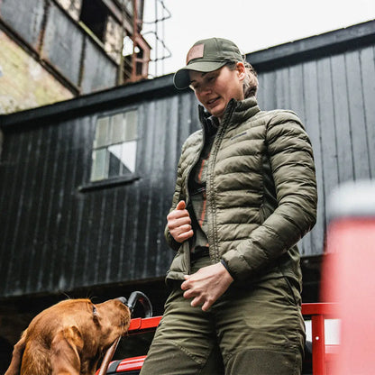 Person in olive green outdoor clothing with brown dog wearing Seeland Therma Jacket