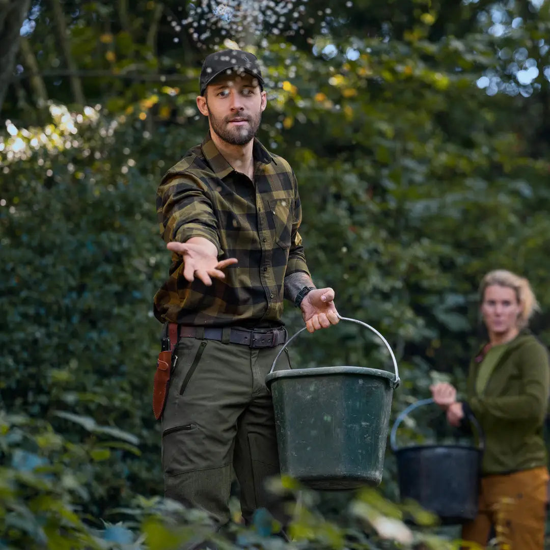 Man in camouflage wearing Seeland Toronto Shirt, holding a bucket outdoors