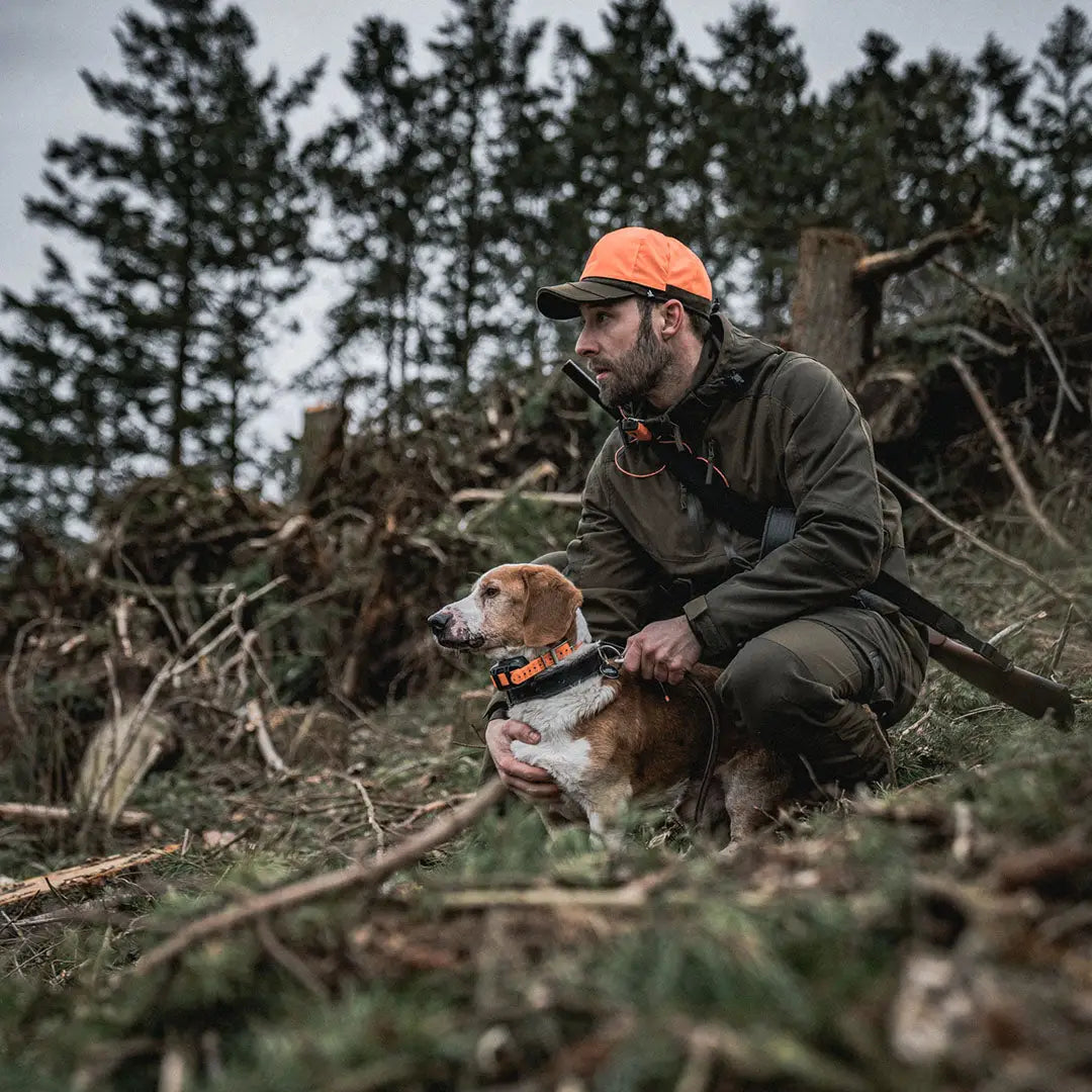 Hunter in orange cap crouching by hunting dog in woods wearing Seeland Trax Cap