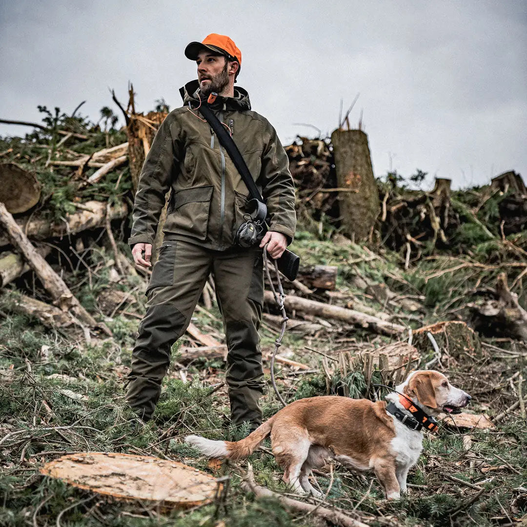 Man in Seeland Trax Jacket stands with dog in a clear forest area