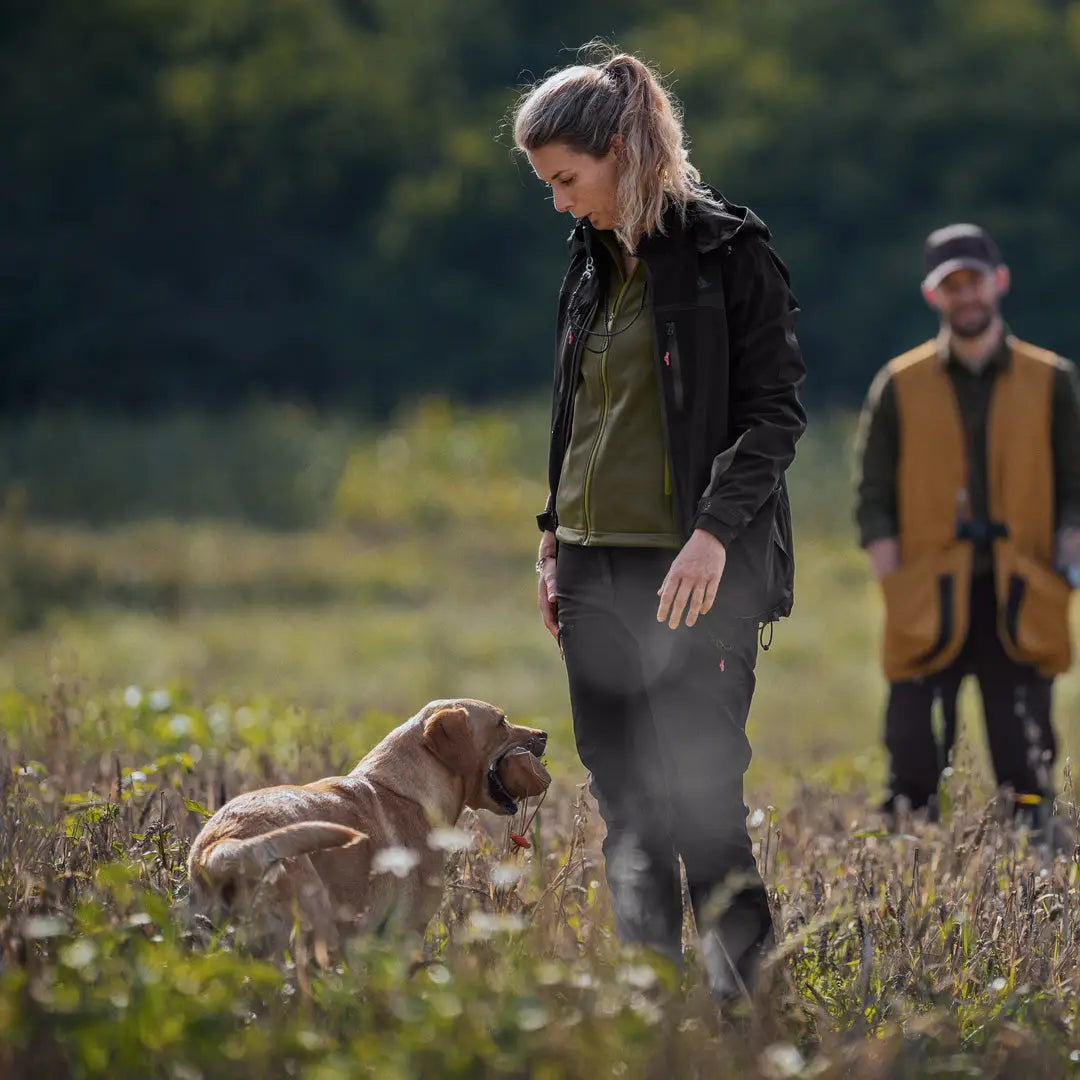 Woman in Seeland Dog Active Jacket walking a dog in a sunny field