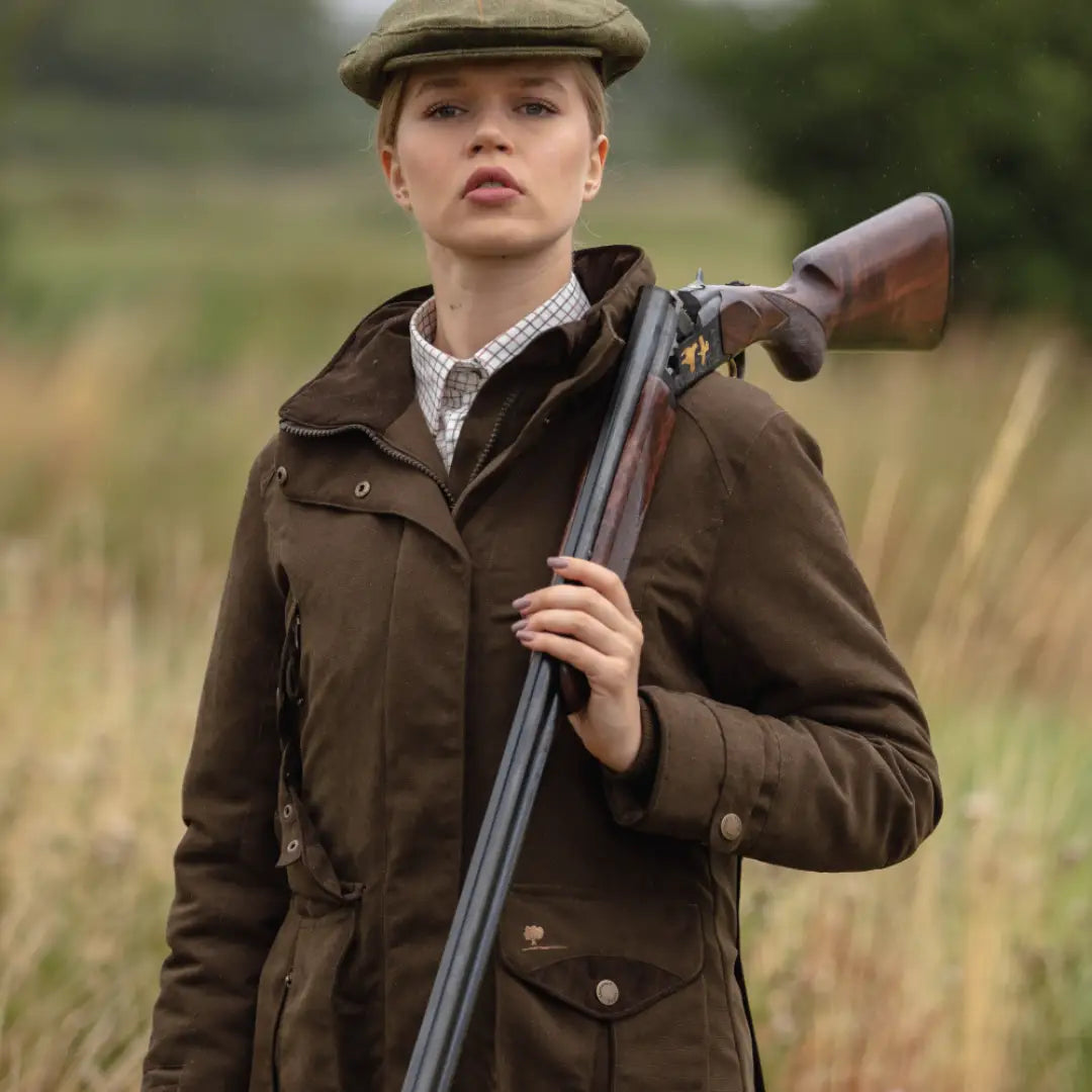 Woman in Sherwood Forest Oakham hunting jacket holding a shotgun in the woods