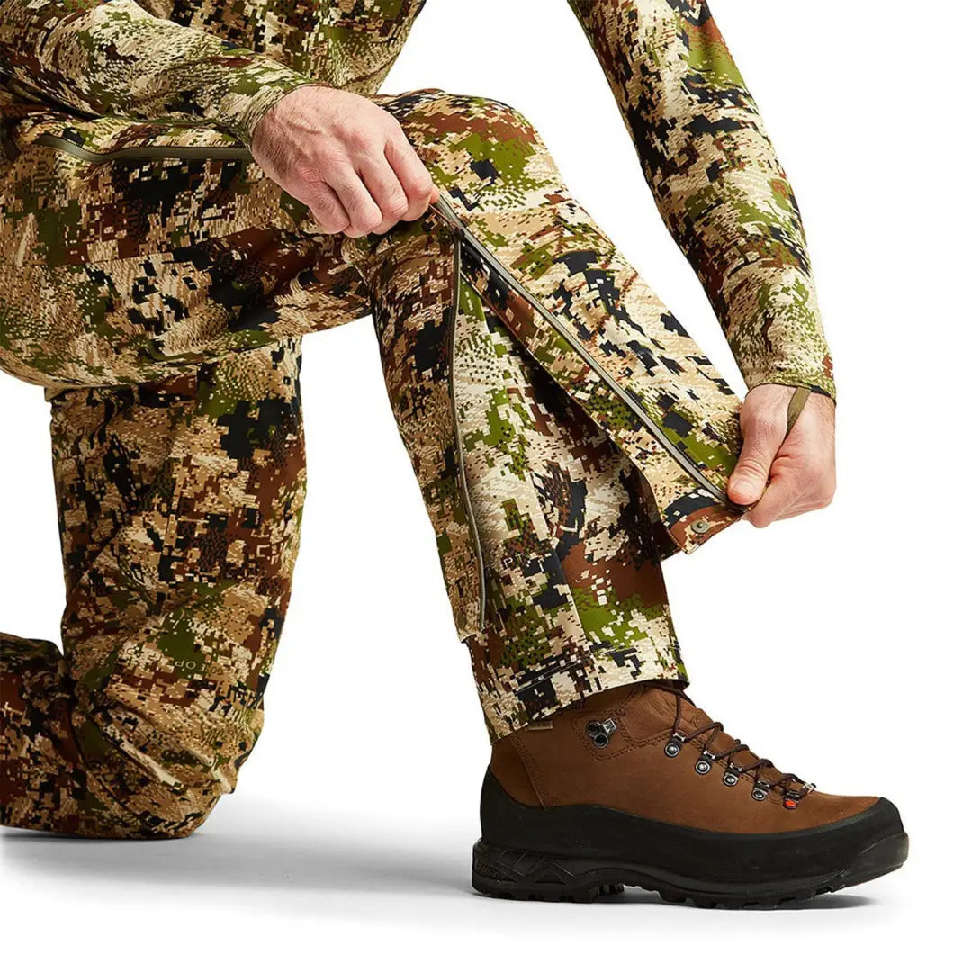 Camouflage Sitka Dew Point Pants with brown hiking boot, featuring 3-layer Gore-Tex Dew