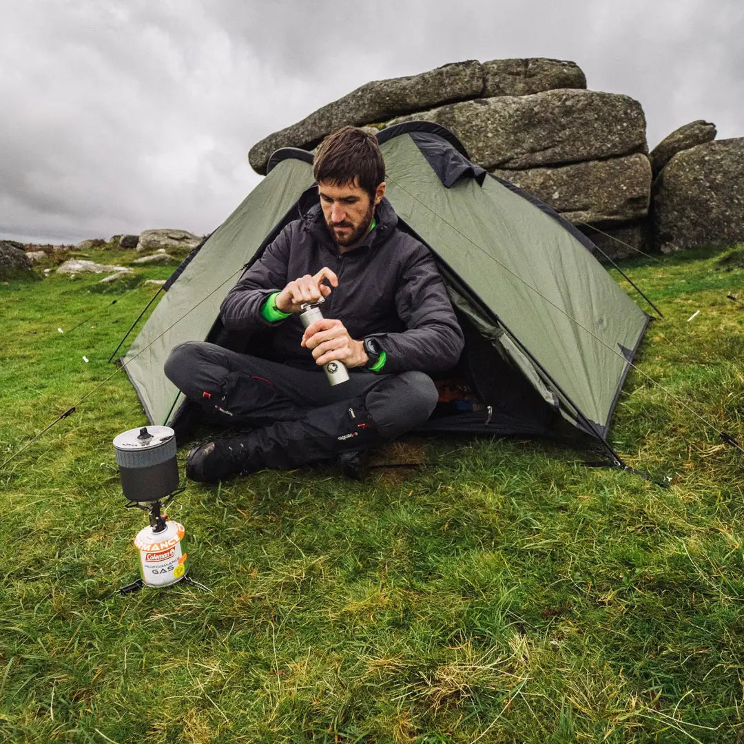 Camper in Snugpak Arrowhead Technical Insulated Jacket cooking outside a green tent