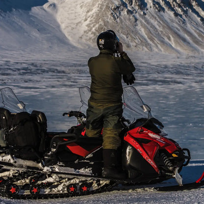 Person on a snowmobile in snowy mountains wearing Snugpak Salopettes Reversible Leg Zip