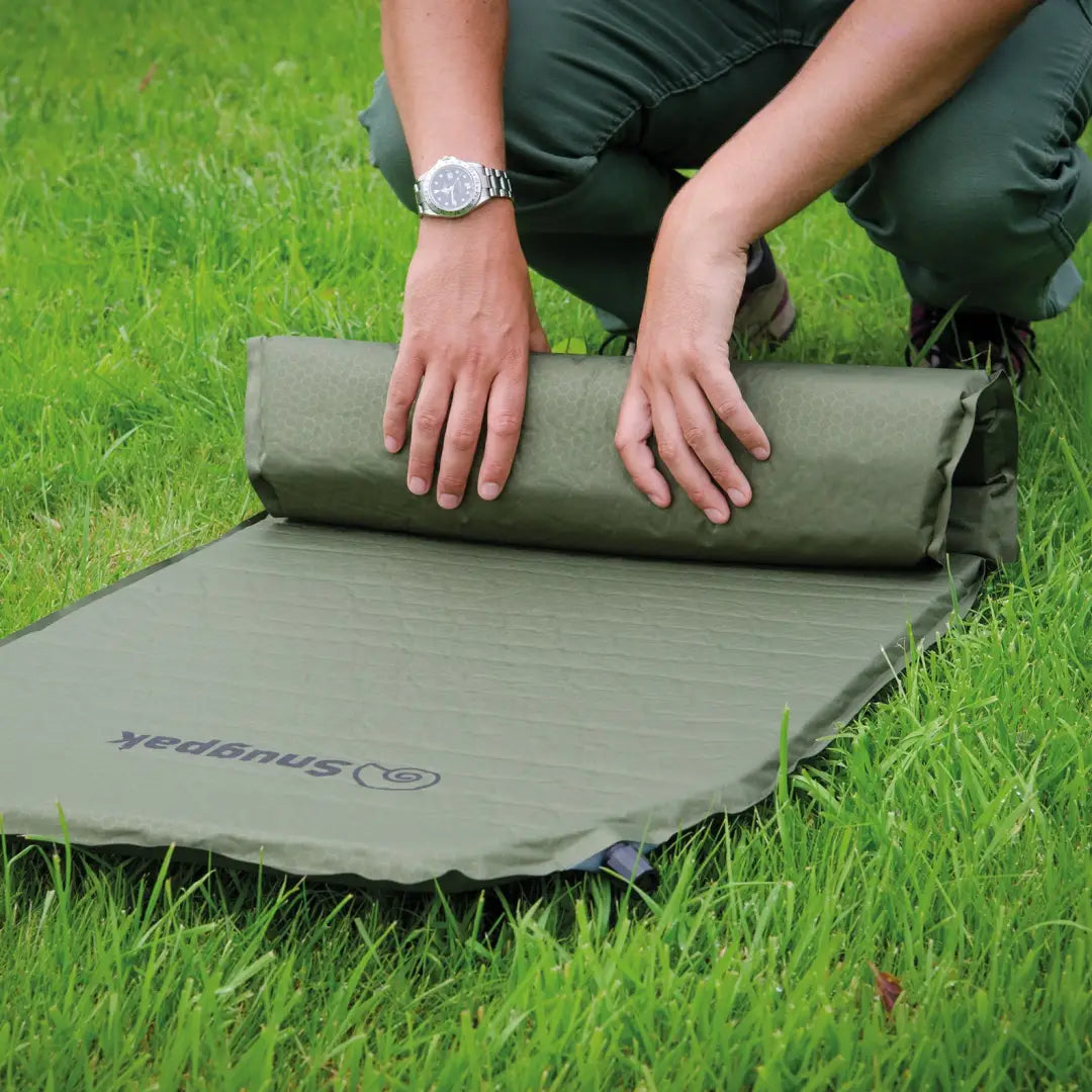 Self-inflating camping mattress unrolled on grass, featuring Snugpak Self-Inflating Maxi Mat