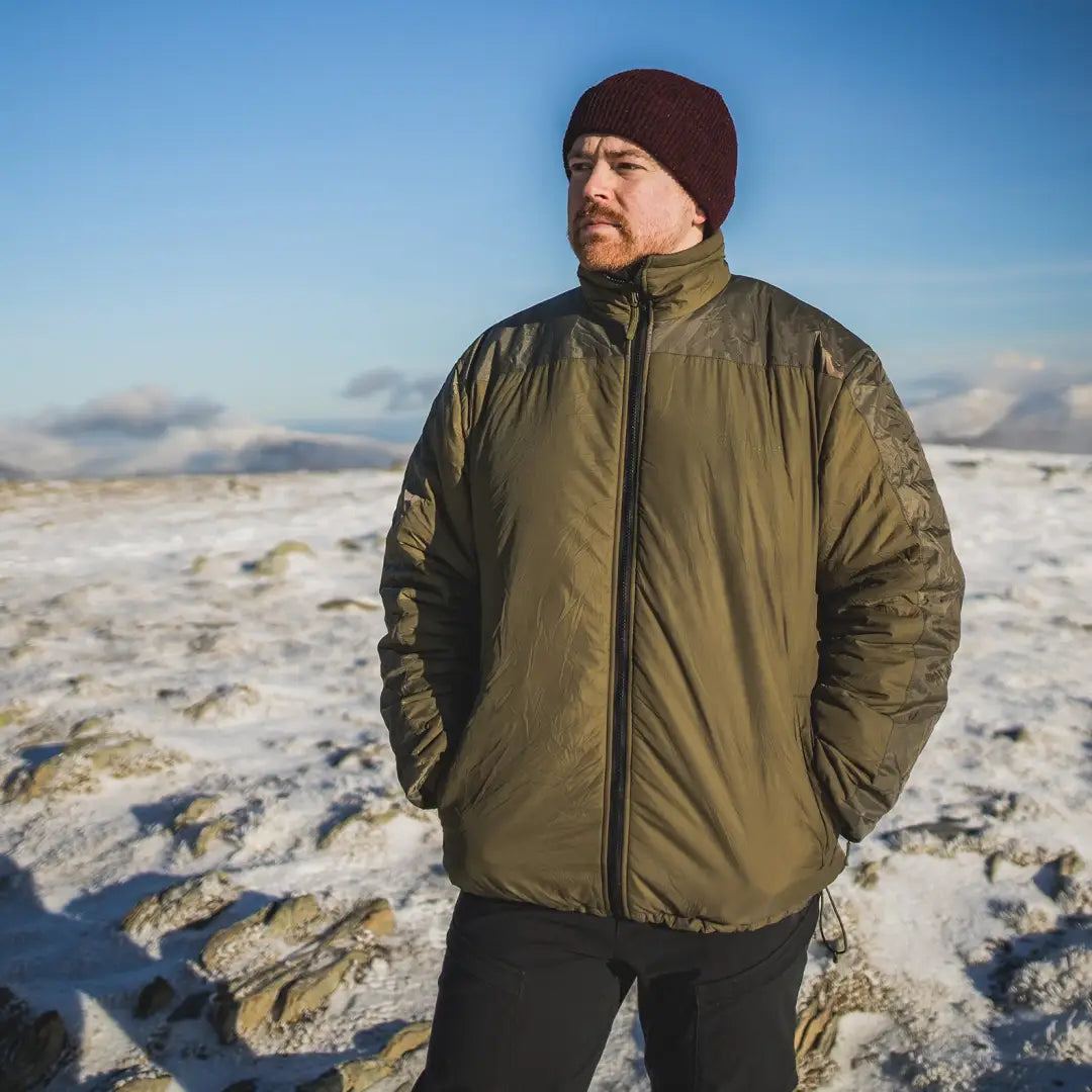 Man in green puffy Sleeka Elite jacket with reinforced patches in snowy landscape