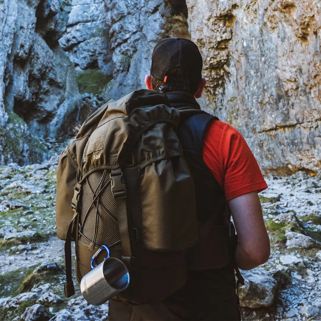 Hiker in red shirt with Snugpak Sleeka Force backpack by rocky cliff showcasing intelligent design