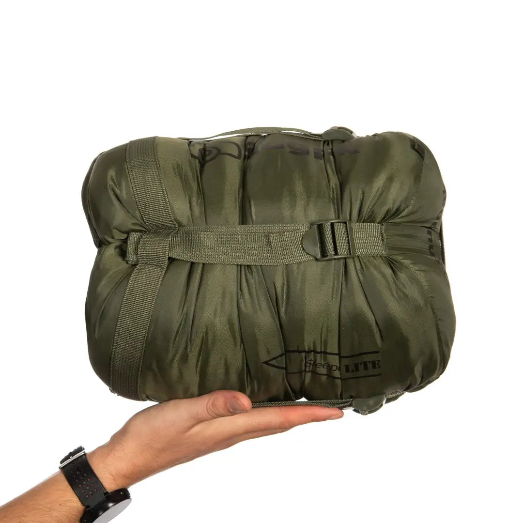 Hand holding Military-style olive green Snugpak Sleeper Lite lightweight sleeping bag