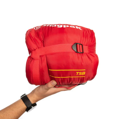 Hand holding a red Snugpak sleeping bag with TSB label, perfect for city lights adventures