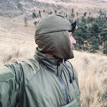 Person in a green hooded jacket outdoors, showcasing Snugpak’s sleeping bags style