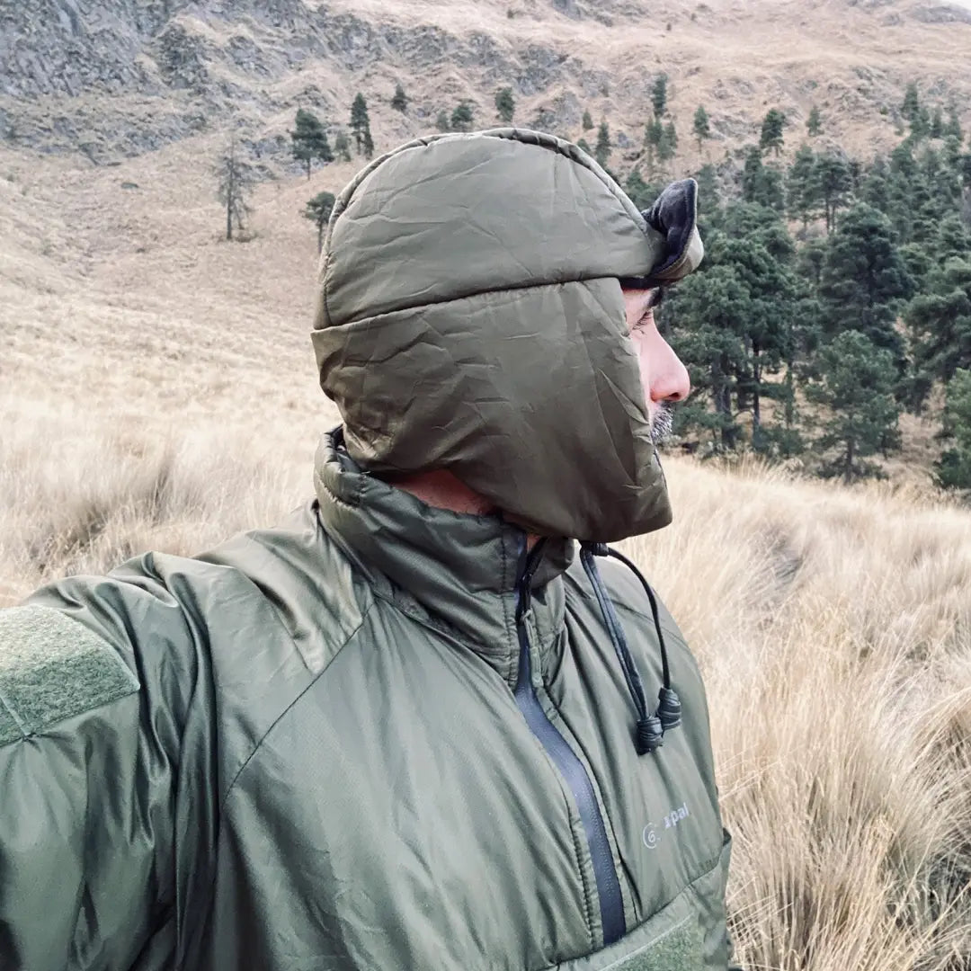 Person in a green hooded jacket enjoying the outdoors with Snugpak Snugnut for extra warmth