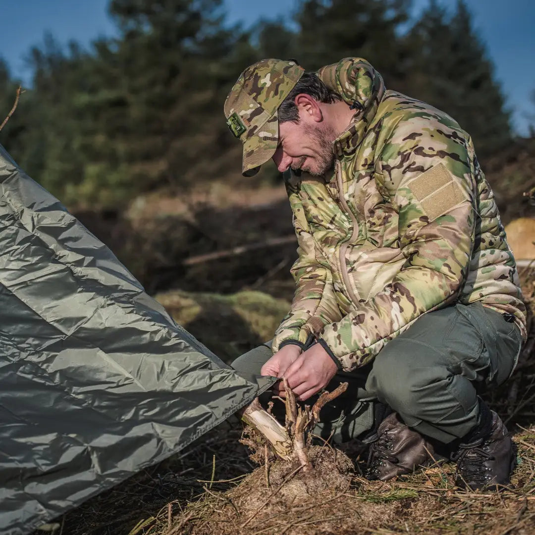 Soldier in camouflage setting up Snugpak Stasha weather shelter for wild camping