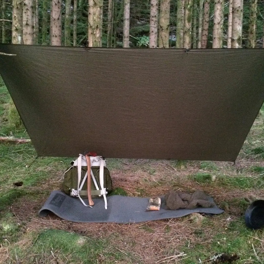 Tarp shelter in trees showcasing Snugpak Stasha for wild camping weather shelter