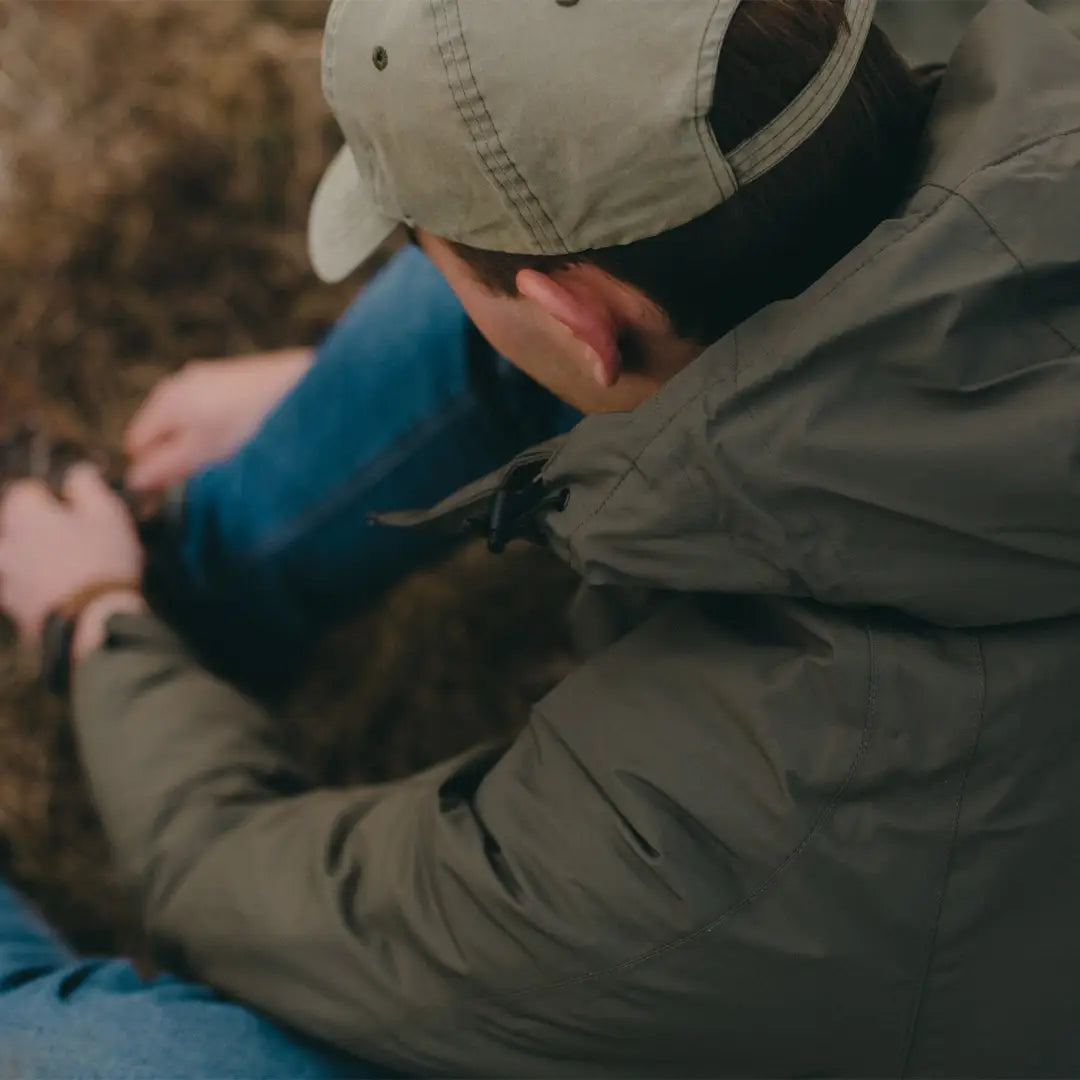 Person in a light cap and jacket leaning forward, showcasing the Snugpak Torrent Jacket