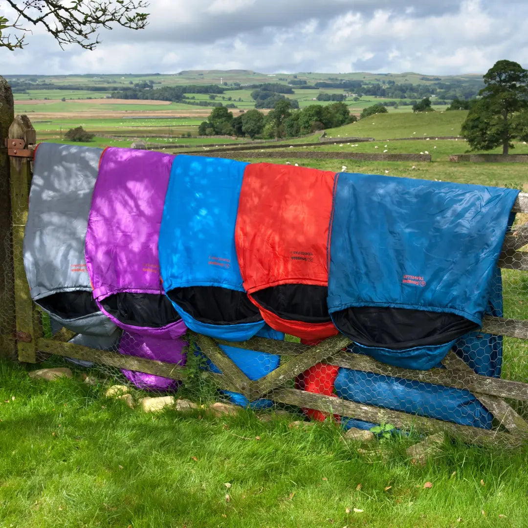 Four colorful folding camping chairs by a fence, perfect for a mosquito-free adventure!