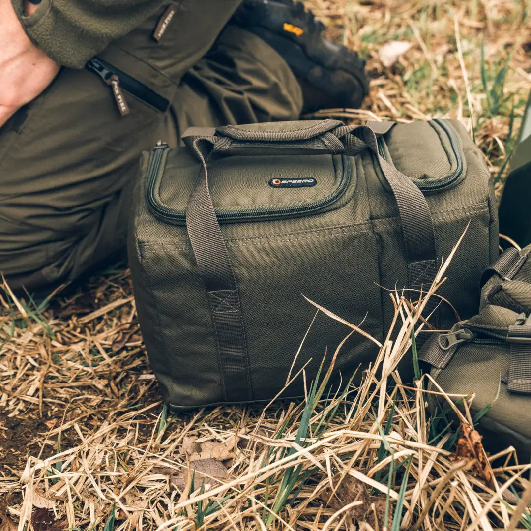 Olive green Speero Brew Kit Bag resting on dry grass, perfect for outdoor adventures