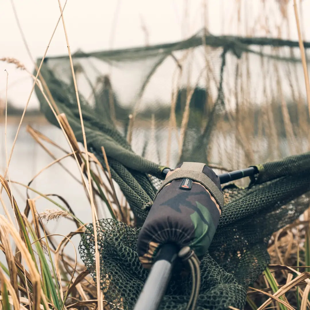 Fishing rod on a camouflage net in grass with Speero Net Retention Float XL nearby