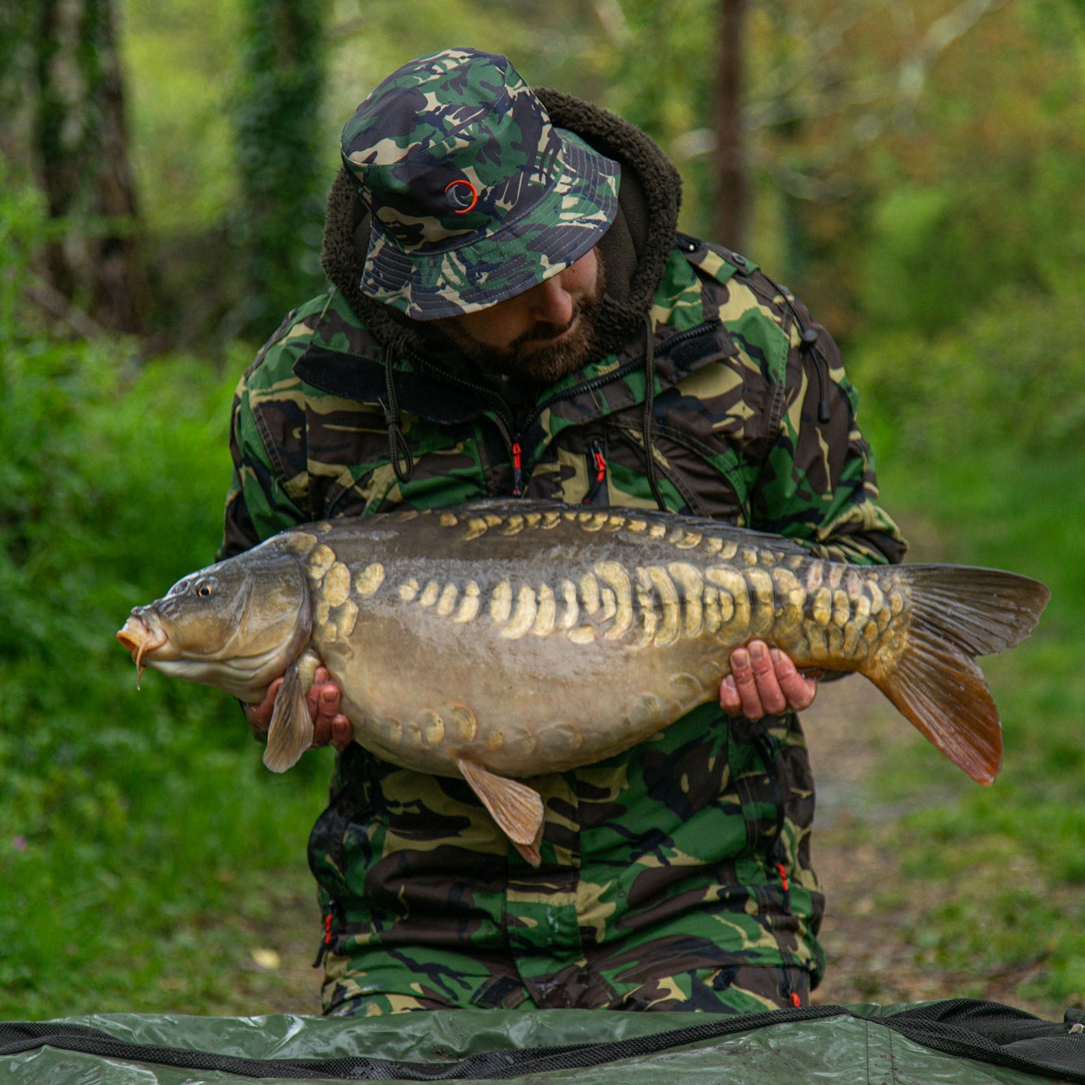 Man holding large carp while wearing a Sirius Tech-Lite Jacket in great weather conditions