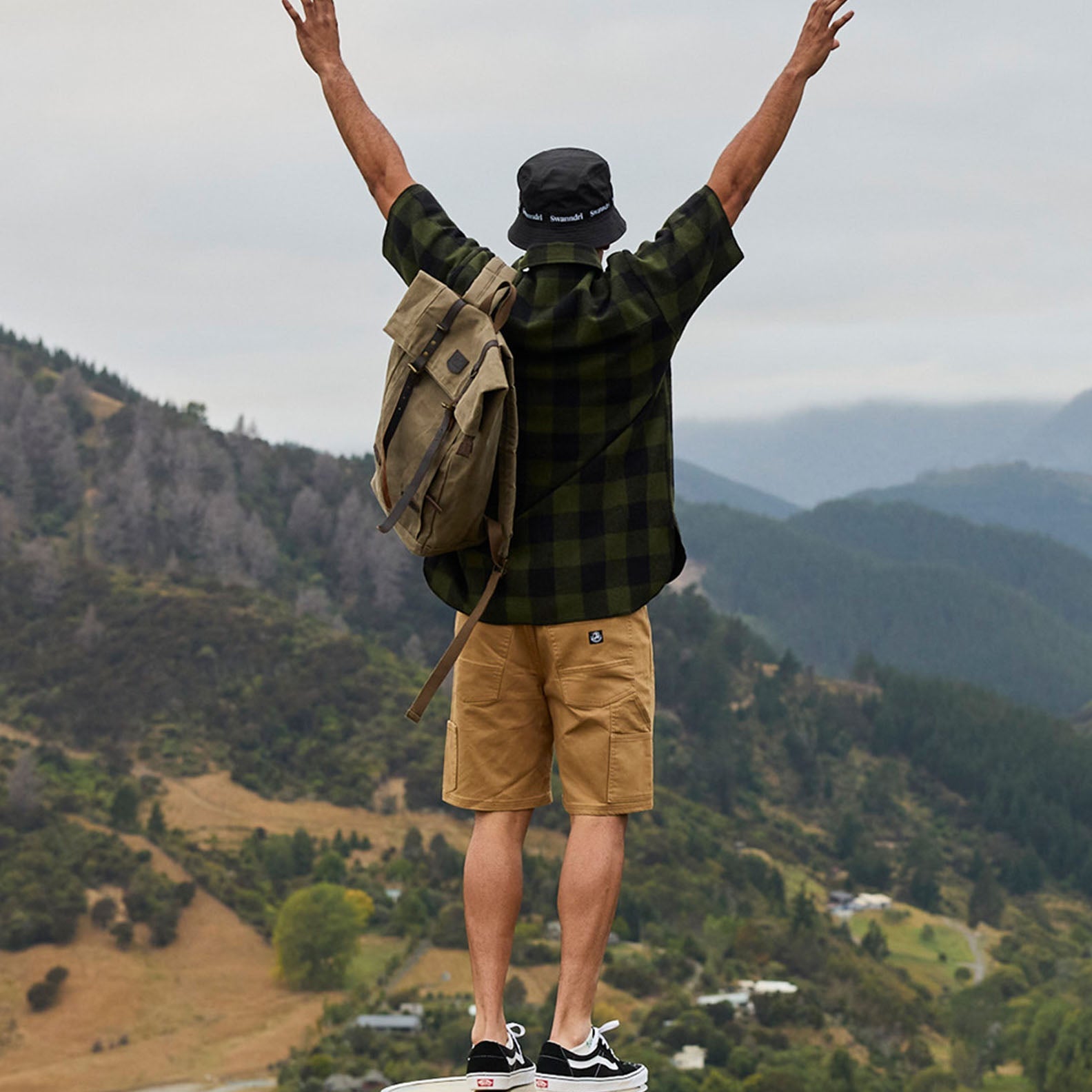 Man with backpack and arms raised wearing a Swanndri Henderson Half Zip Jacket