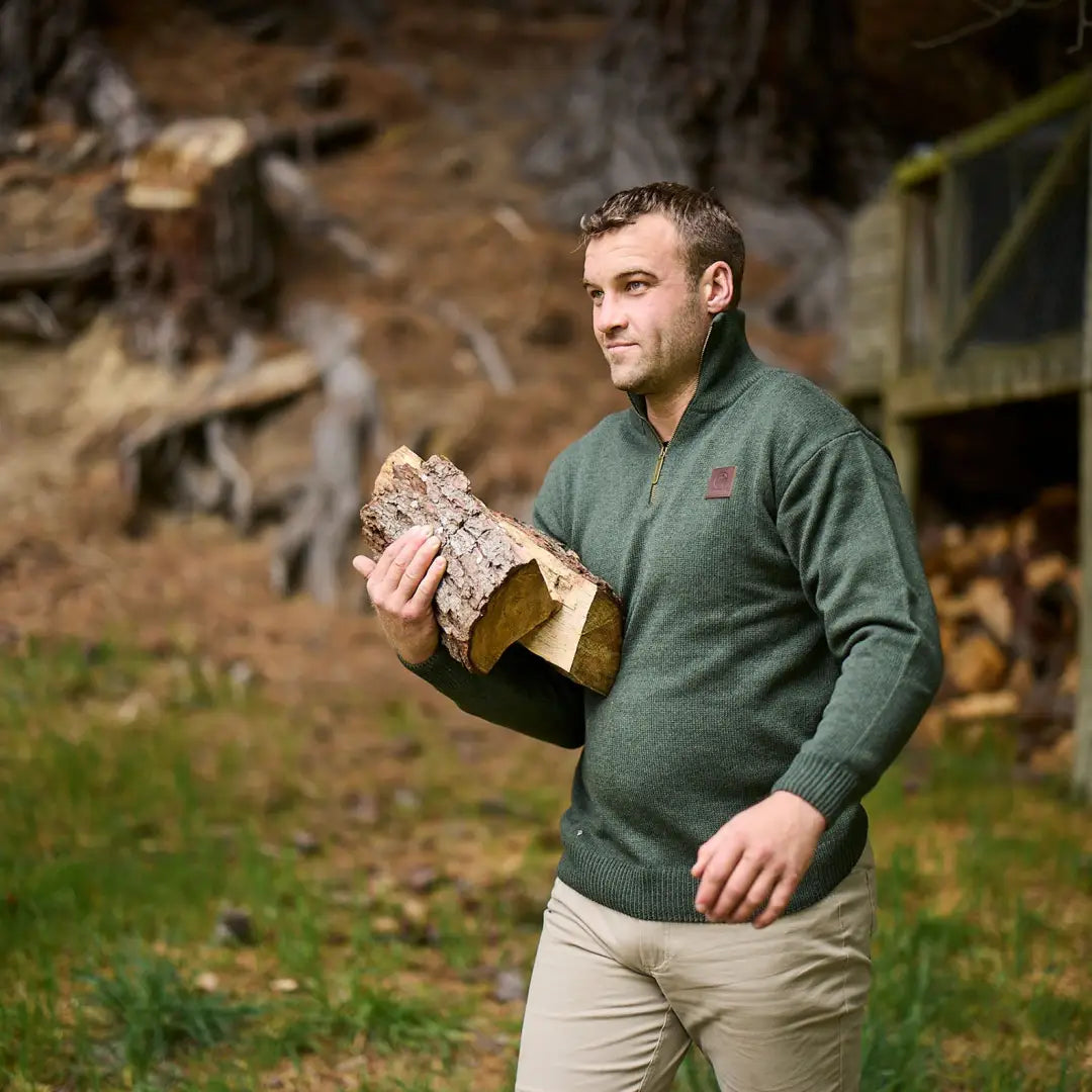 Man in a green pullover jumper with shetland wool, holding firewood in style