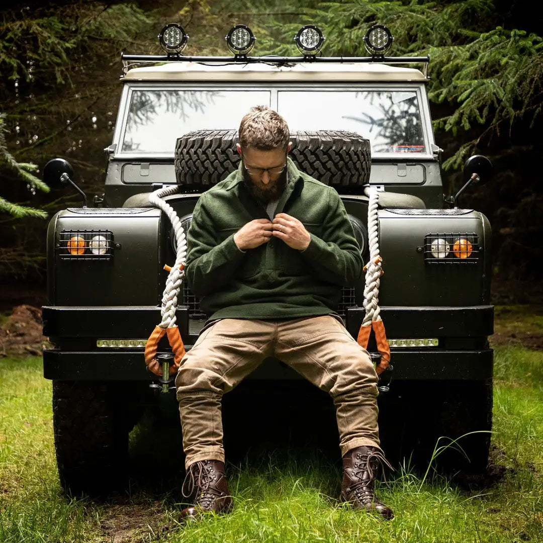 Rugged off-road vehicle with a person on the bumper, featuring Swanndri Ranger Extreme V2