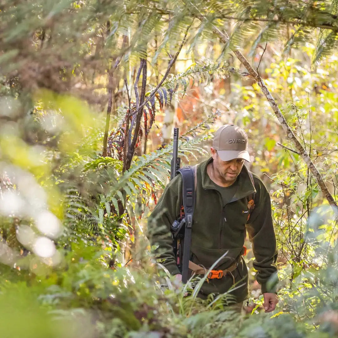 Hunter in Swazi Doughroaster Fleece trekking through dense forest vegetation