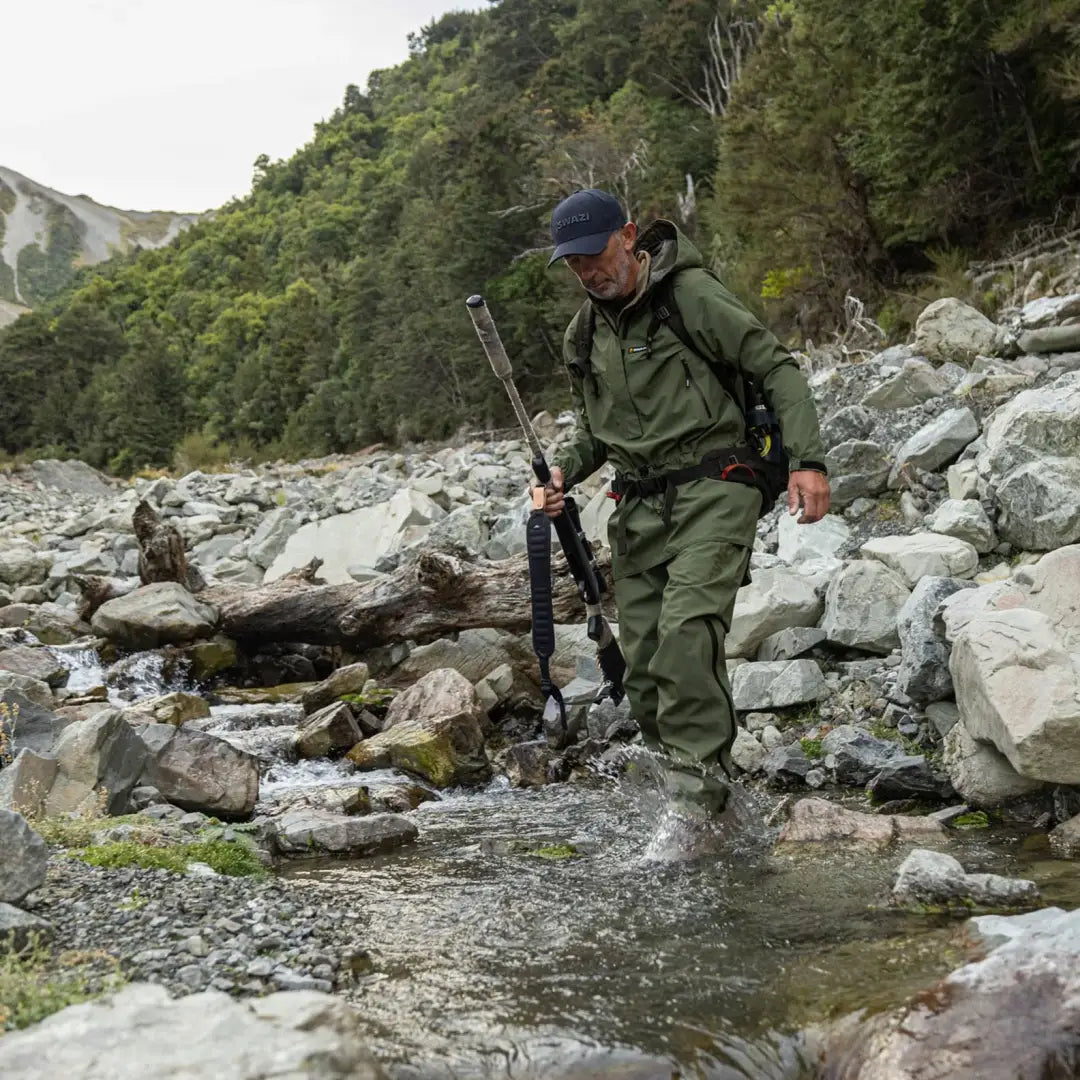 Hiker crossing a stream in a Swazi Tahr Ultralight Jacket with 20k waterproof feature