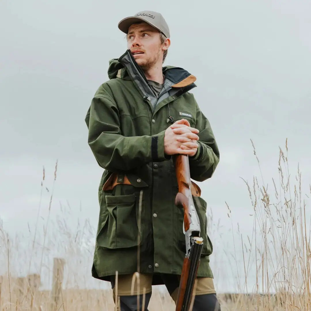 Man in green Swazi Wapiti XP Jacket holding rifle, perfect for outdoors person wanting style