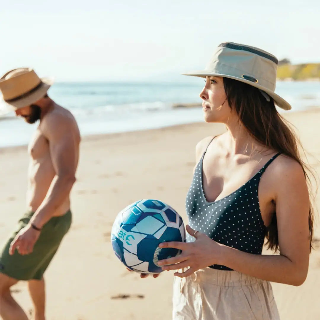 Woman in a sun hat enjoying the beach with a Tilley Airflo Hat and beach ball