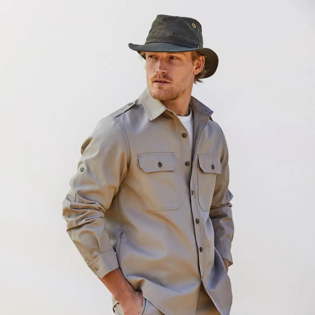 Man in khaki shirt and dark hat showcasing the Tilley TH5 Hemp Hat with sloped brim design