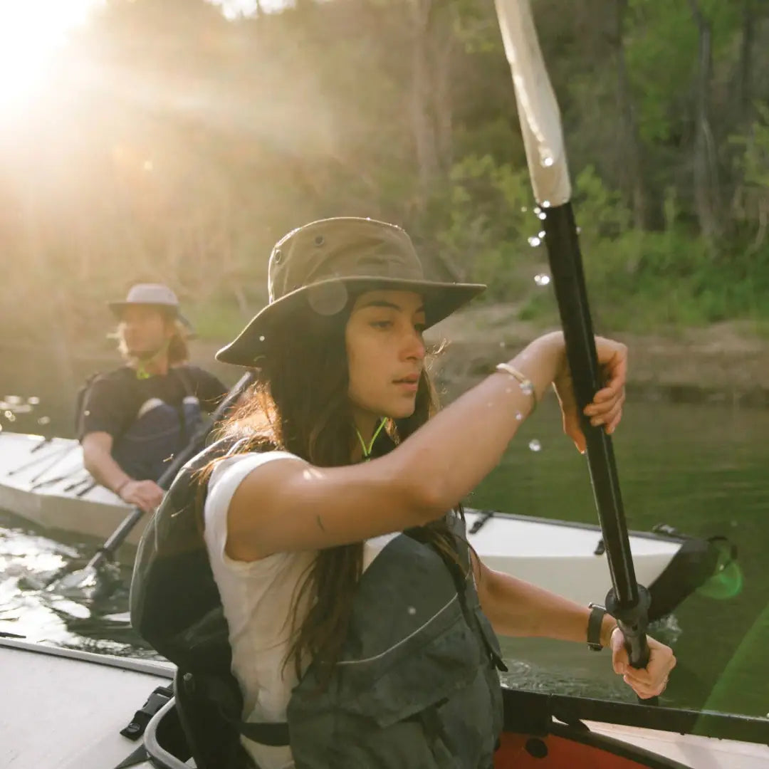 Woman in a Tilley TWS1 weather hat and life vest paddling a kayak on the water