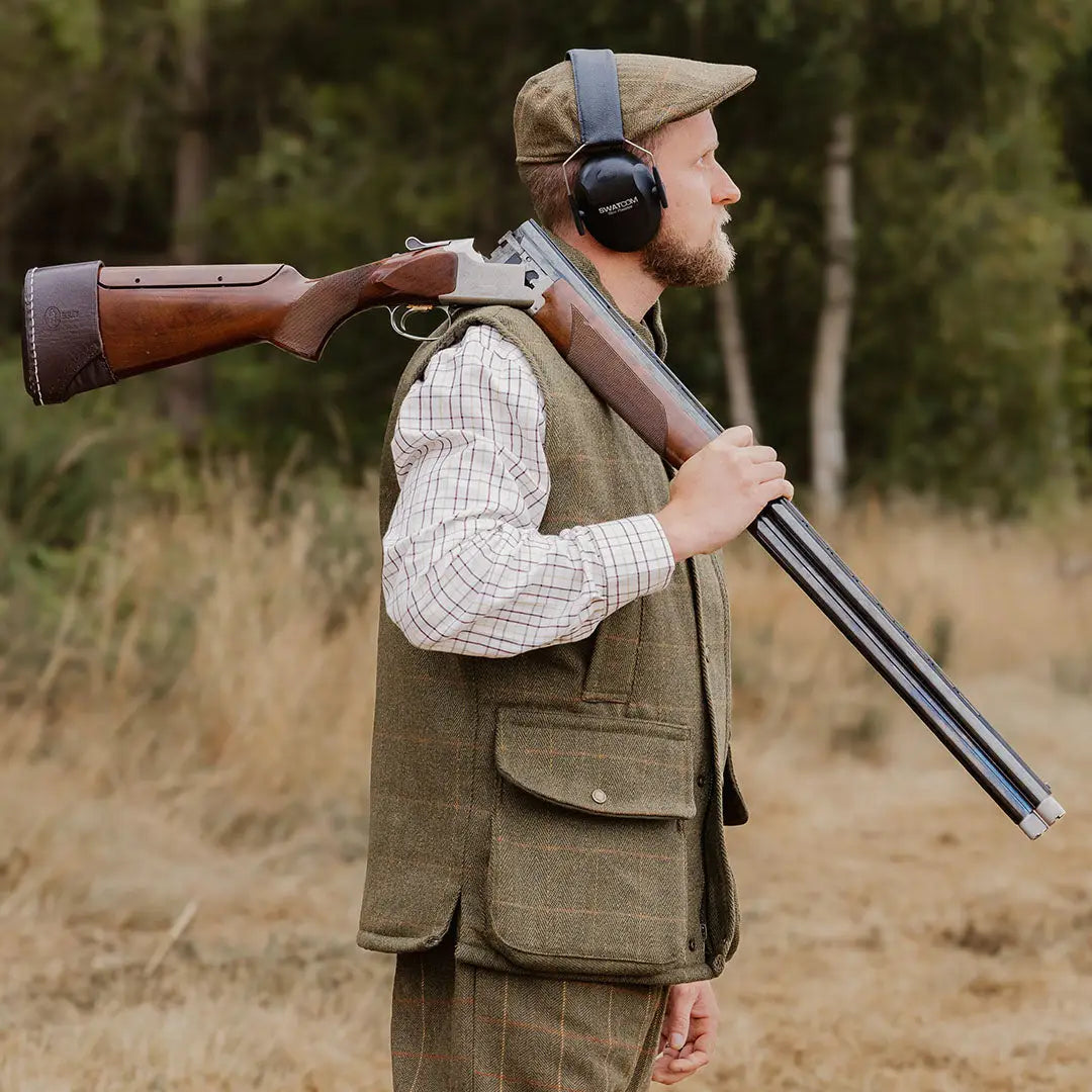 Hunter in tweed gilet showcasing shotgun, perfect for country activities and clothing