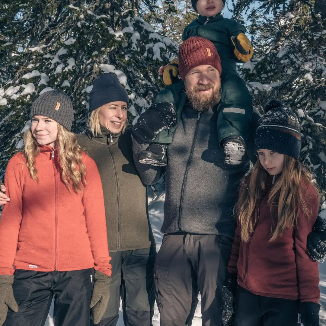 Family decked out in winter gear with snowy forest and Woolpower zip jacket vibes